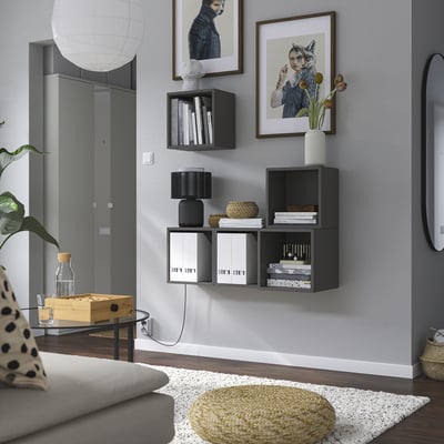 Modern living room with white couch, coffee table, plant, & EKET storage units filled with books & decor.
