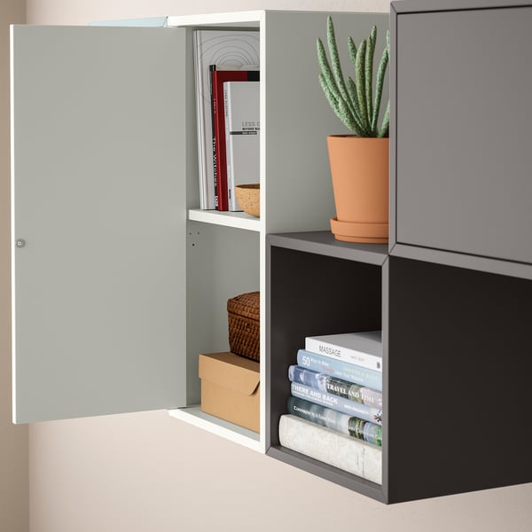 Wall-mounted EKET cabinet with open shelves, a movable shelf, and a door, holding books and a plant.