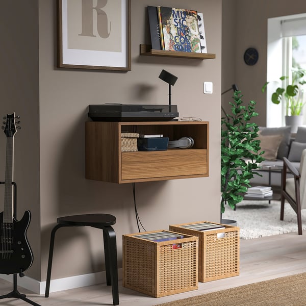 Modern record player with wicker storage, wall poster, clock, and plant.