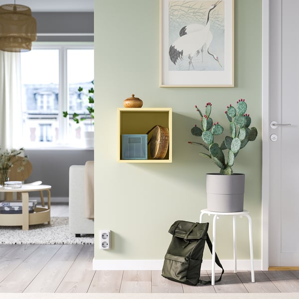 Green EKET cabinet with decor, cactus, backpack, crane print, window view.