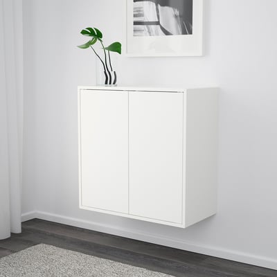 White wall-mounted storage cabinet with two doors and a potted plant on top.
