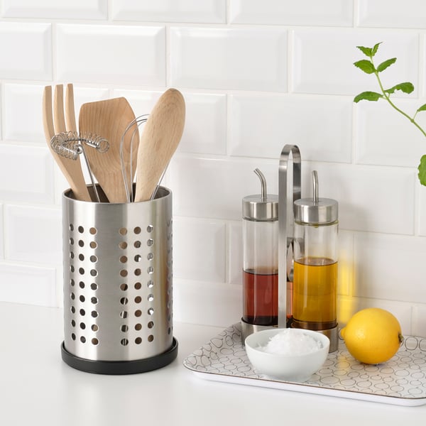Kitchen counter with wooden utensils, oil dispensers, lemon, salt, and tray under utensil holder for draining water.