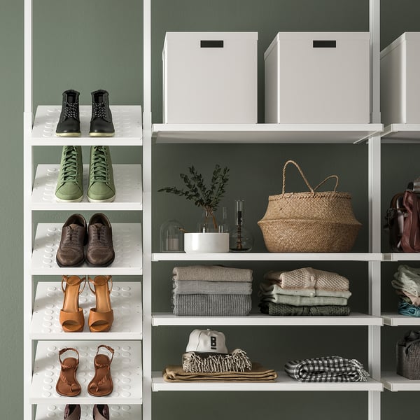 Organised closet with shoes, clothes, wicker bag, and decorative items on white shelves.