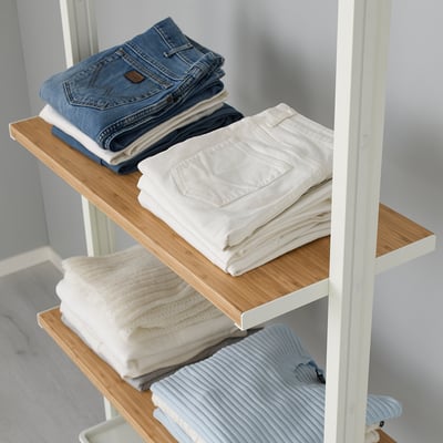 Folded clothes organised on wooden shelves, part of a modular storage system.