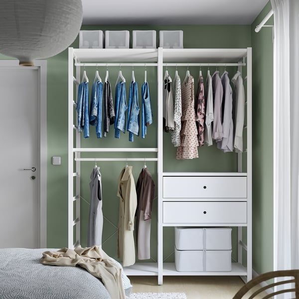 White closet with shelves, drawers, green walls, bed.