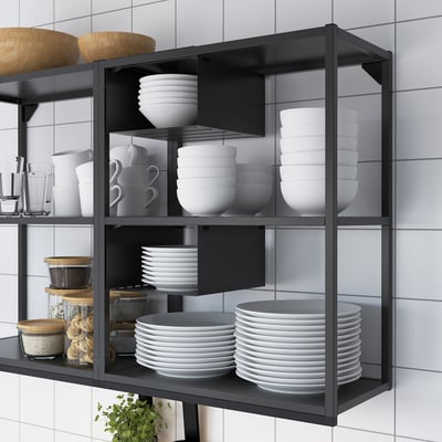Black metal kitchen shelf holding white dishes, bowls, mugs, and jars. Organises and displays kitchenware neatly.