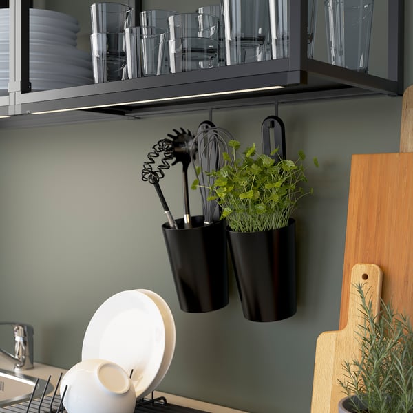 Kitchen wall storage shows hooks holding utensils and hanging plants.
