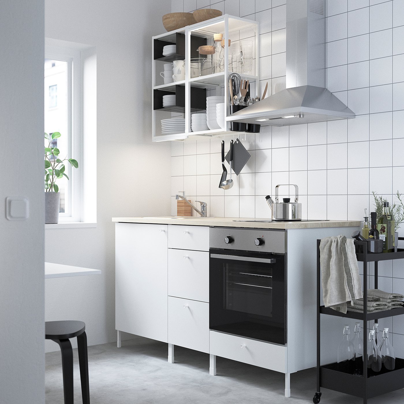 Modern white kitchen setup with integrated oven, open shelves, black rolling cart, and hanging plants.
