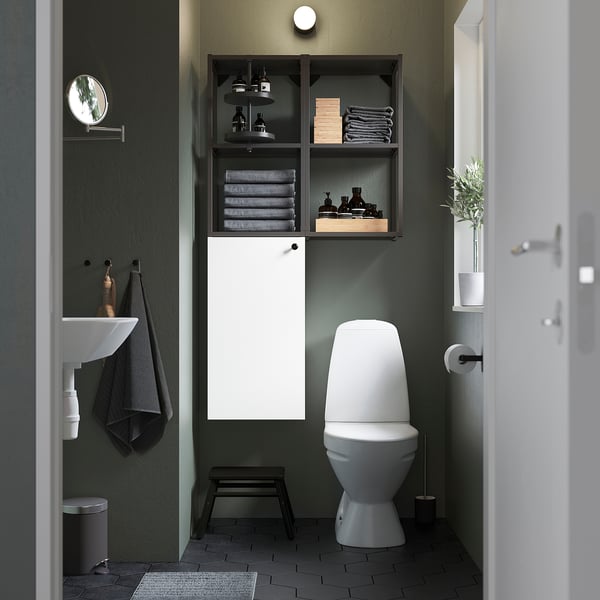 Modern bathroom ENHET white cabinet, sleek toilet. Dark green walls add contrast. Towels and toiletries organised neatly.