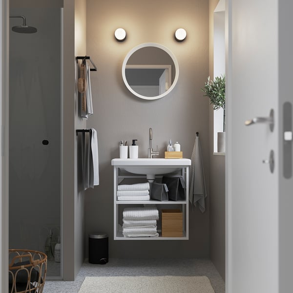 Modern bathroom: wall-mounted white sink with round mirror, minimalist style.