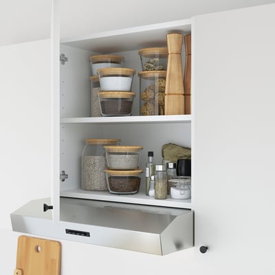 White kitchen cabinet storing glass containers and wooden board; ideal for small items.