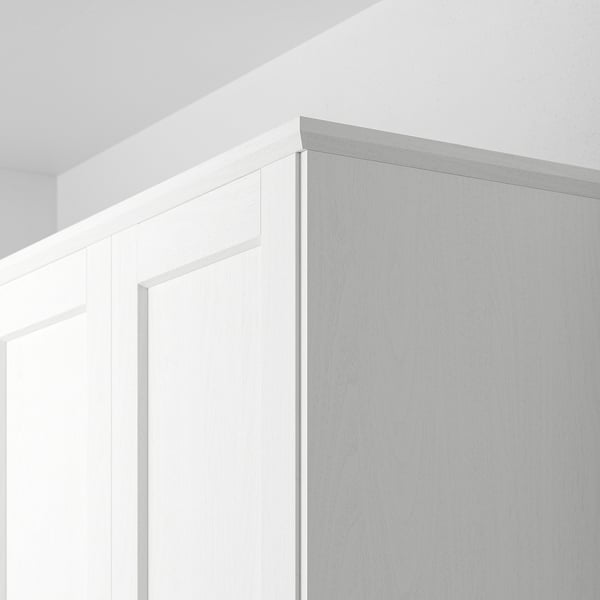 White cabinet trim, positioned at corner, hiding lighting units, blending with wall.