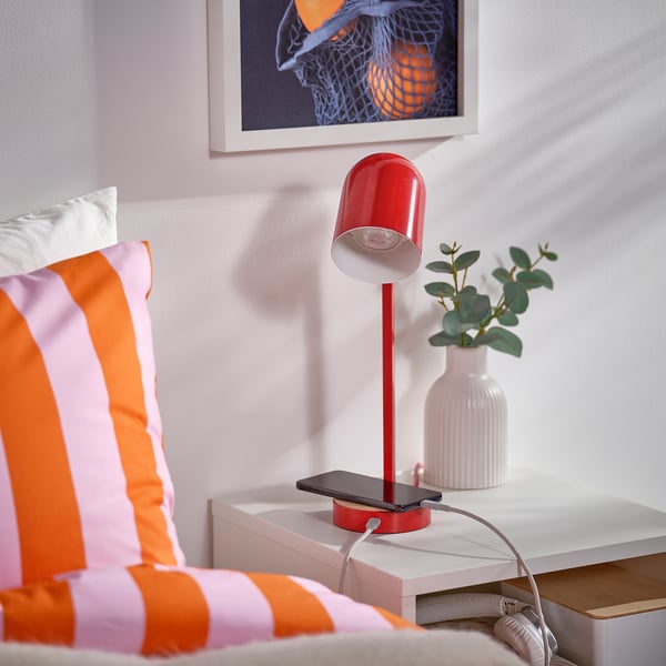 Bright red desk lamp with usb-c charging, brightening workspace beside colourful pillows.