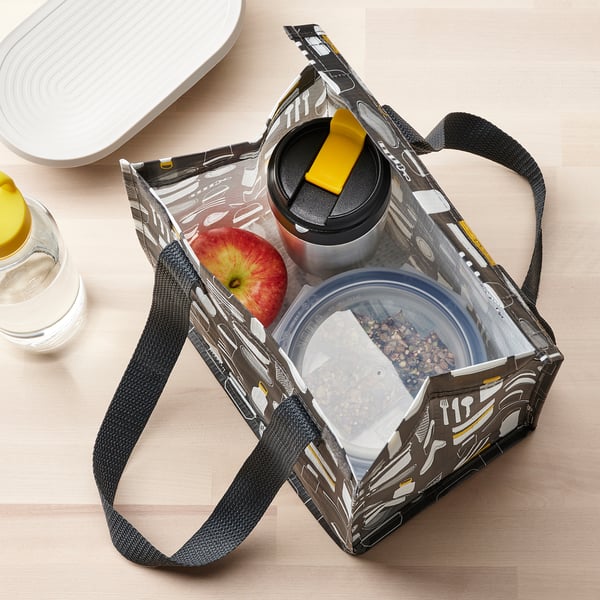 Insulated travel mug in bag with apple and snacks, ideal for on-the-go.
