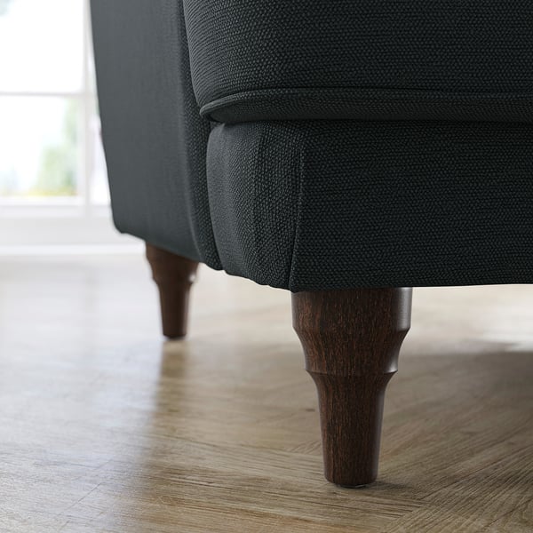 Dark grey upholstered sofa with wooden legs on hardwood floor.