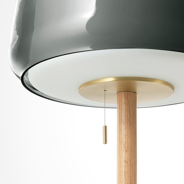 Elegant lamp with grey glass shade, brass accents, and wooden base. Highlights craftsmanship and quality.