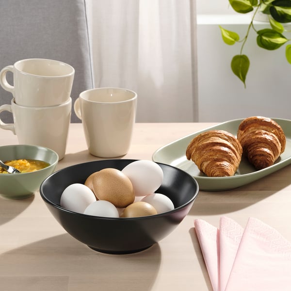 Breakfast table set with bowls, croissants, mugs, and napkins.