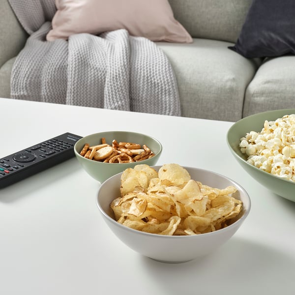 Three bowls of snacks and a tv remote on a coffee table.