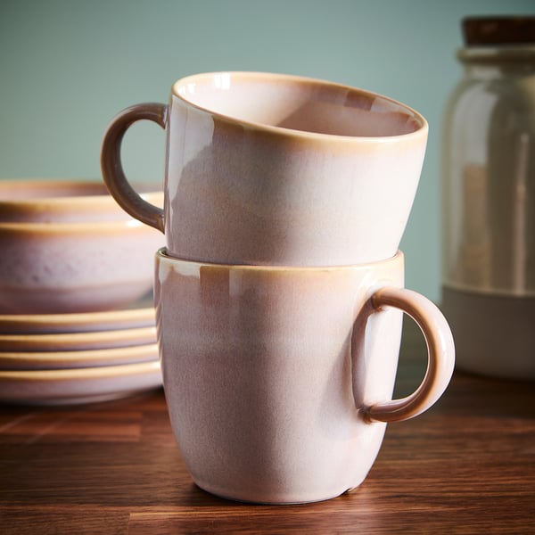 Two rustic mugs stacked on wooden table. Perfect for coffee or tea, showcasing simple design and unique handcrafted glaze.