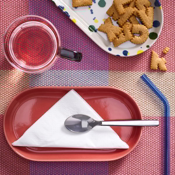 Table setting with fantastik white napkins, red plate, pink drink, blue straw, and animal crackers.