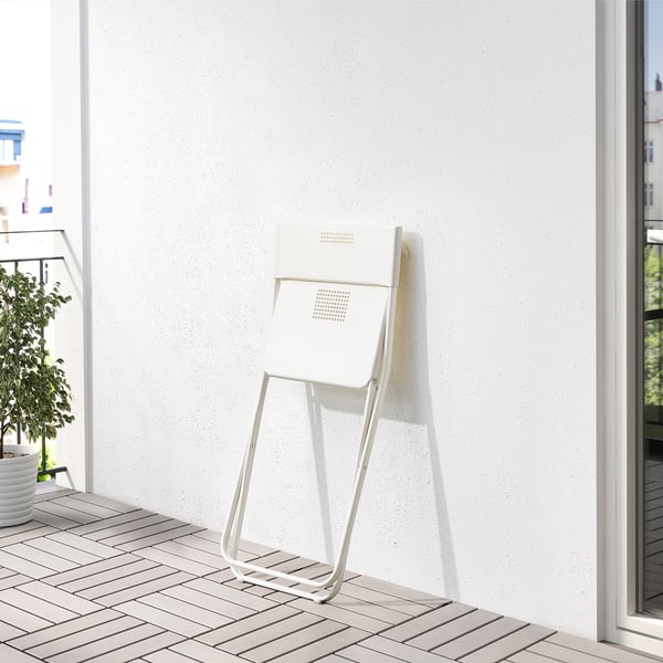 Foldable white chair on tiled balcony, perfect for small spaces.