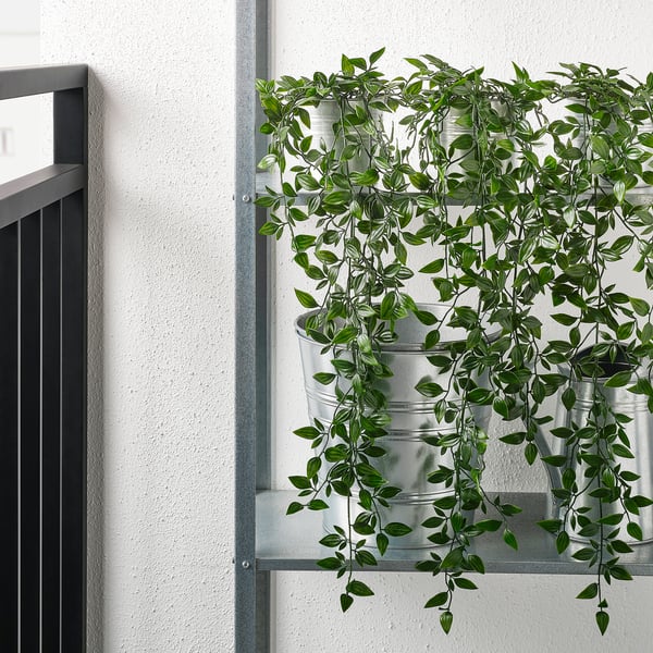 Artificial greenery in metal pots on a window ledge, adding indoor nature.