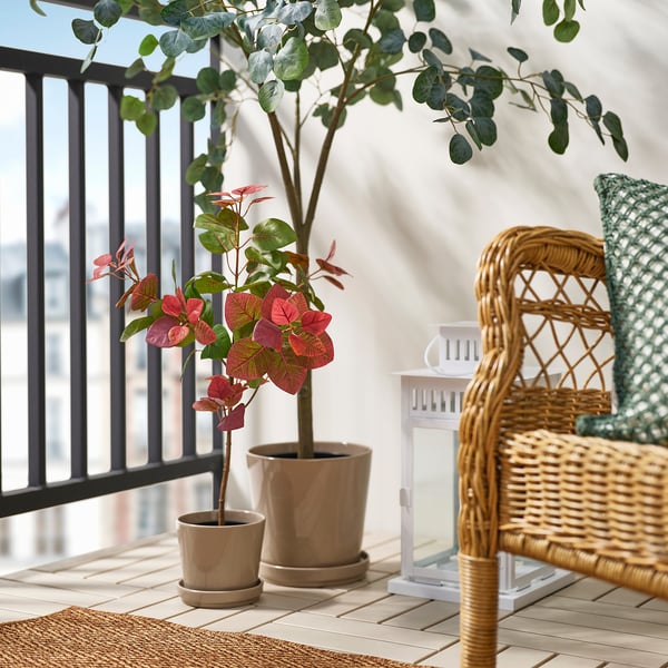 Balcony with wicker chair, plant, and lantern.
