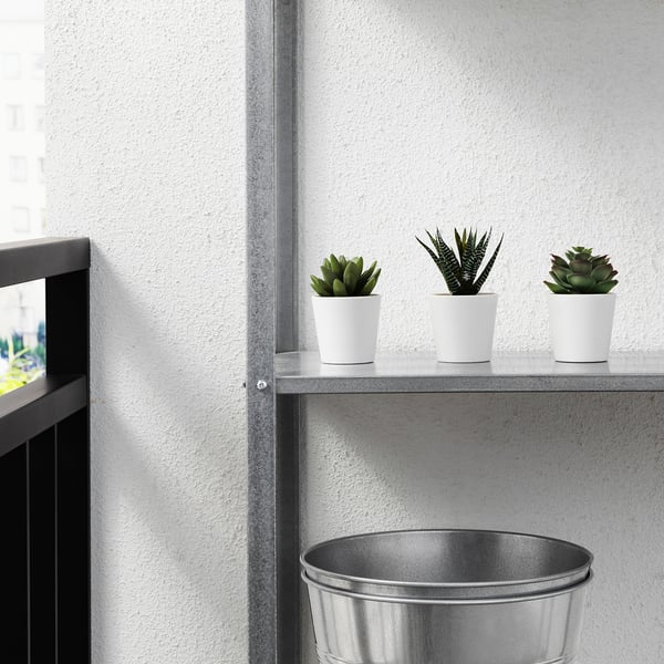 Three white potted artificial succulents on a grey shelf against a white wall, perfect for low-maintenance indoor or outdoor decor.