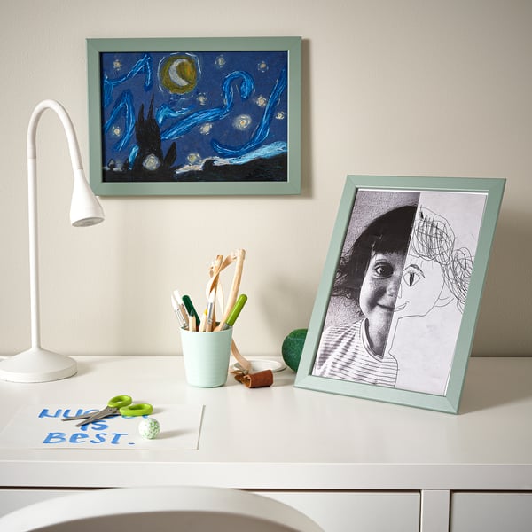 Desk with art supplies, two drawings: one black-white sketch, one blue night sky, lamp.