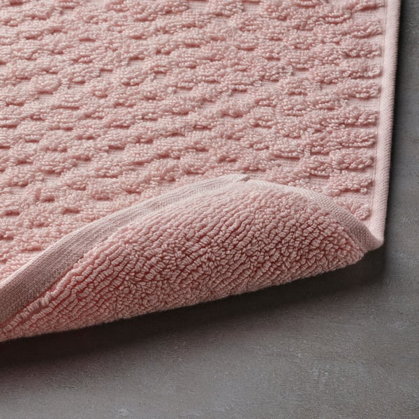 Soft, textured light pink bath mat, terry cloth for comfort and quick absorption.