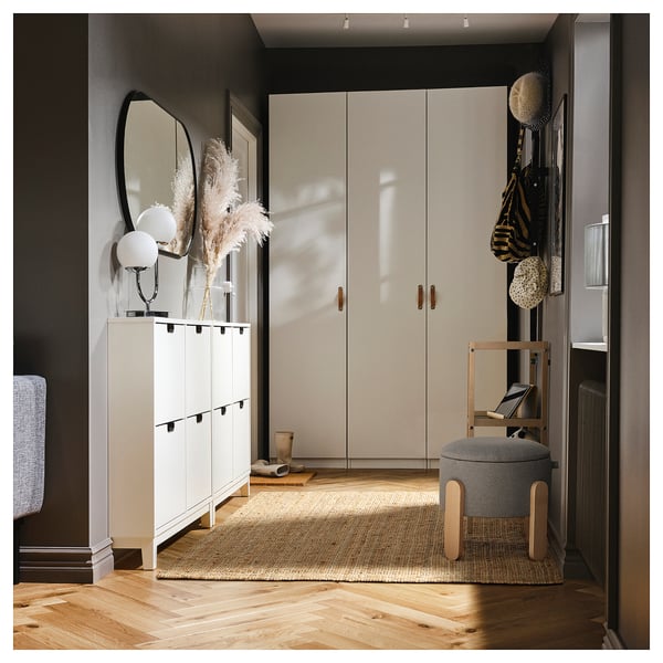 Minimalist hallway white cabinets, large mirror, stylish stool, wooden floor, jute rug, and hanging decor.