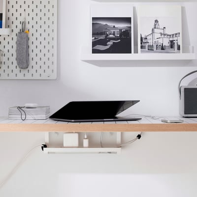 Minimalist white workspace: laptop, speakers, accessories on shelves; small FÖRSÄSONG tray manages cables neatly.