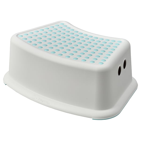 A white FÖRSIKTIG step stool with blue, non-slip dots on top. Its square-shaped with rounded edges and two small holes on the side for carrying.