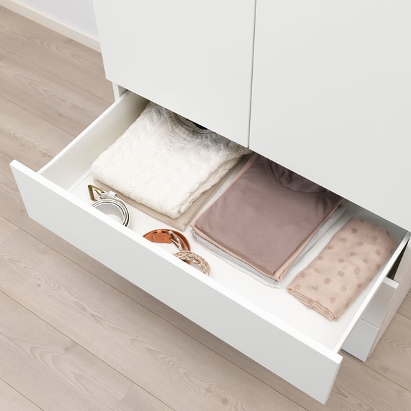 White platsa drawer open showing folded clothes, demonstrating storage capacity.