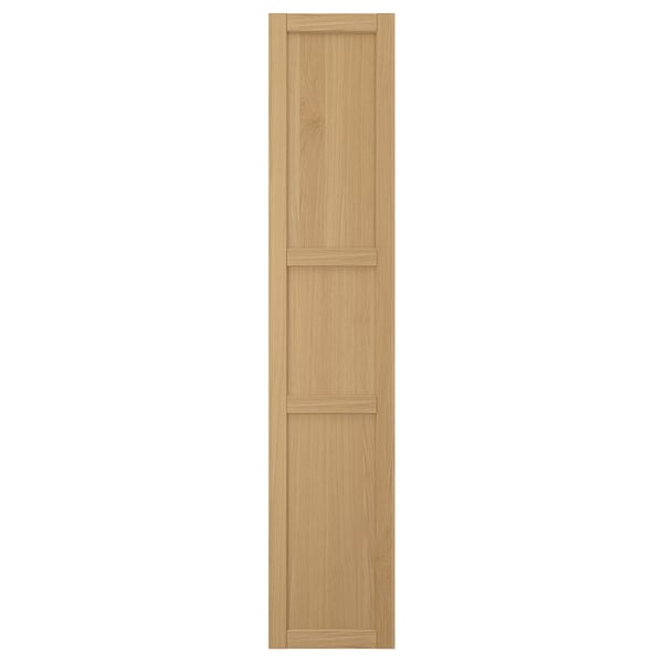 A FORSBACKA kitchen cabinet door in warm oak veneer. It a classic framed design with bevelled edges and a natural wood look.