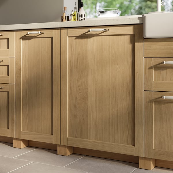 Modern wooden kitchen cabinets in natural oak with bevelled edges, featuring silver handles.
