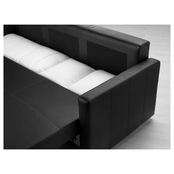 Black leather sofa bed with white mattress folded out, showing storage underneath.