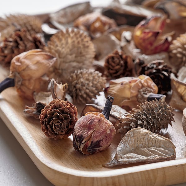 Wooden bowl filled with mixed dried natural items, like pinecones and leaves, arranged neatly.