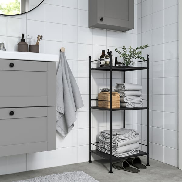 Modern bathroom with grey frosjon shelf, holding towels, next to a cabinet and mirror.