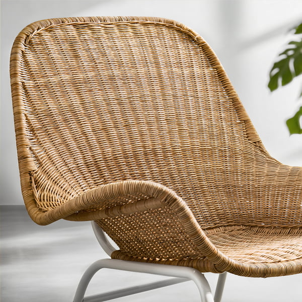 Wicker armchair with curved back and arms, made from handwoven rattan, showing natural texture and light, comfortable design.