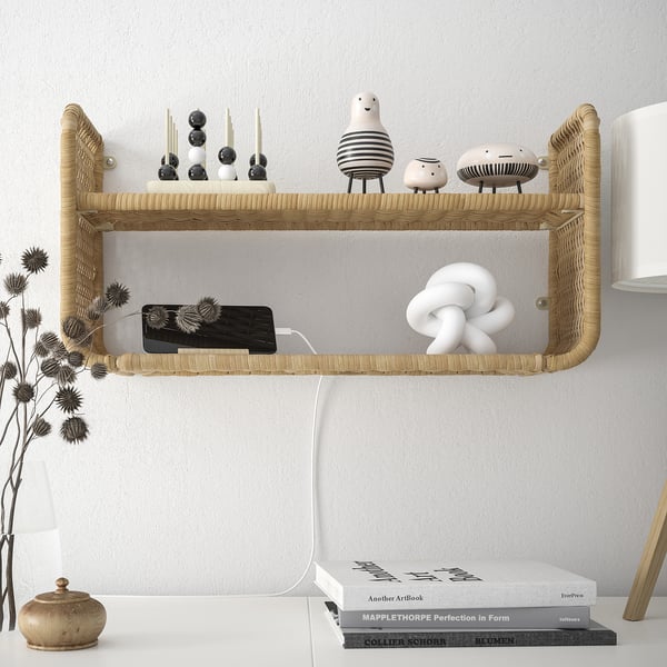 Wall shelf, FRYKSÅS, holds decorative items and charges devices. Shows natural rattan, small and large decor, and phone charging setup.