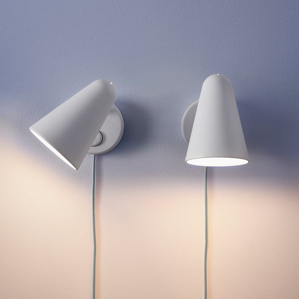 Two modern, adjustable wall lamps in white with a dimming feature, suitable for reading. One lamp is tilted. They are mounted on a grey wall.
