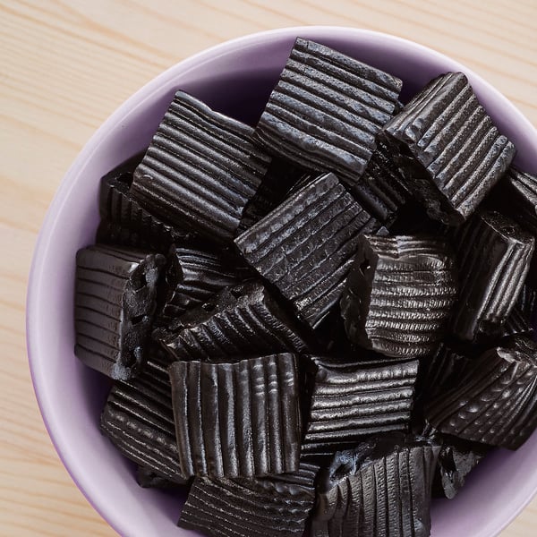 Bowl of black licorice candies, square with ridges.