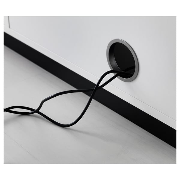 Cord outlet on back of a white desk, managing cable clutter.