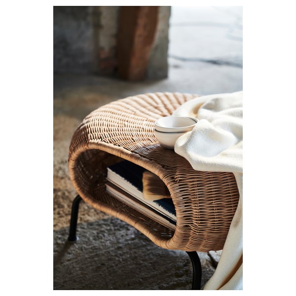 Wicker stool with white blanket and cup, natural materials, semi-circular design.