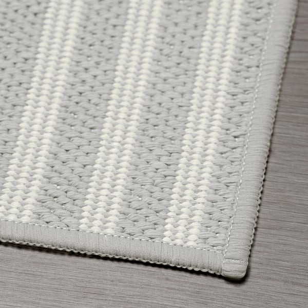Textured, grey woven kitchen mat on a wooden floor, showcasing quality craftsmanship and design.