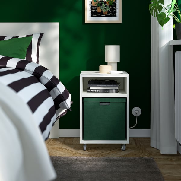 Green velvet GJÄTTA storage box beside bed, mobile with books, fits under bed.
