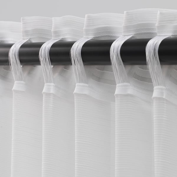 Sheer white curtains on black rod, allowing light with privacy.