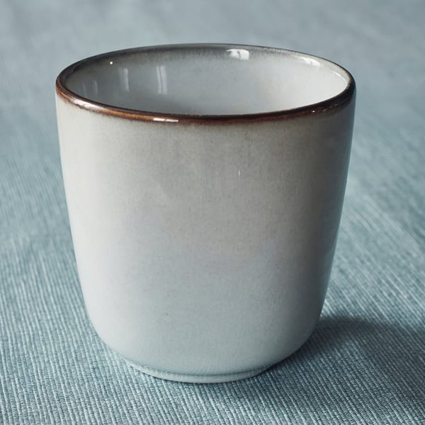 Gradient glaze mug on blue fabric, well-crafted with smooth edge.