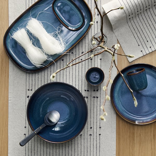 GLADELIG: blue stoneware plate, large, round, handcrafted look, sits beside spoon and napkin, on striped cloth.